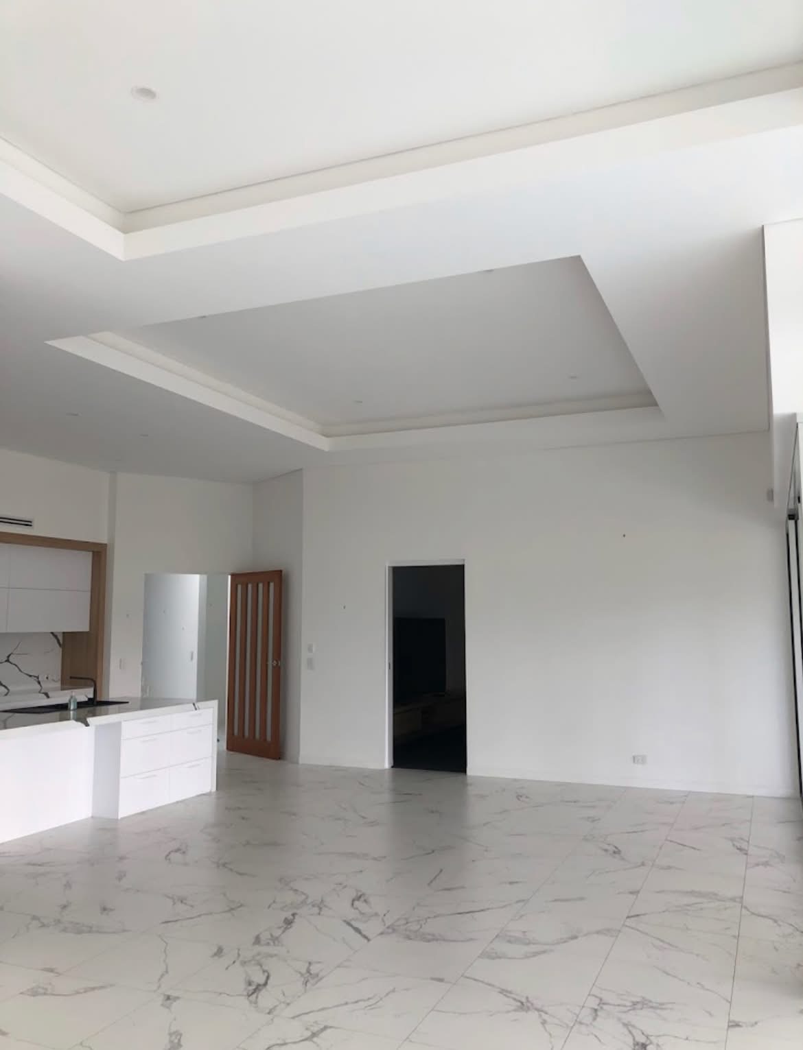 Freshly painted white open-plan interior with a recessed ceiling and marble-look tiles