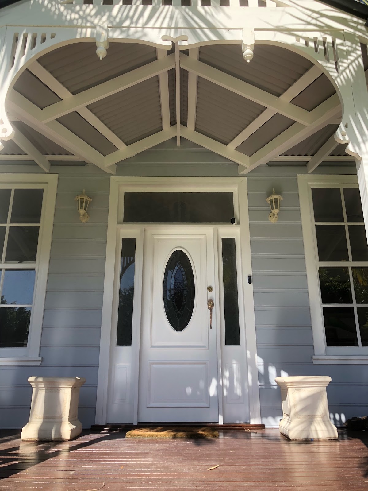 Queenslander front entry with arched white fretwork and a white front door