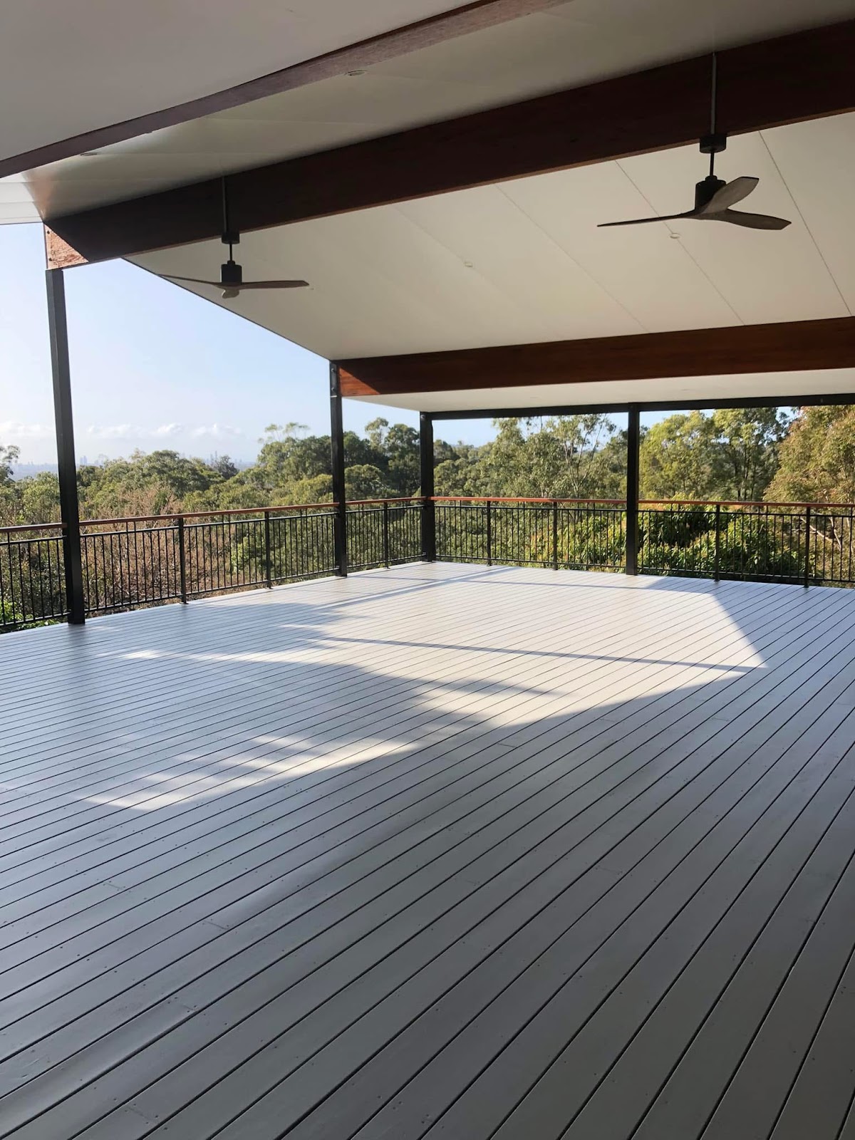 Large painted grey deck under a raked ceiling with a bush view